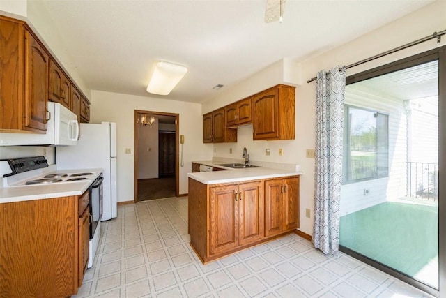 kitchen with white appliances, brown cabinetry, a sink, and light countertops