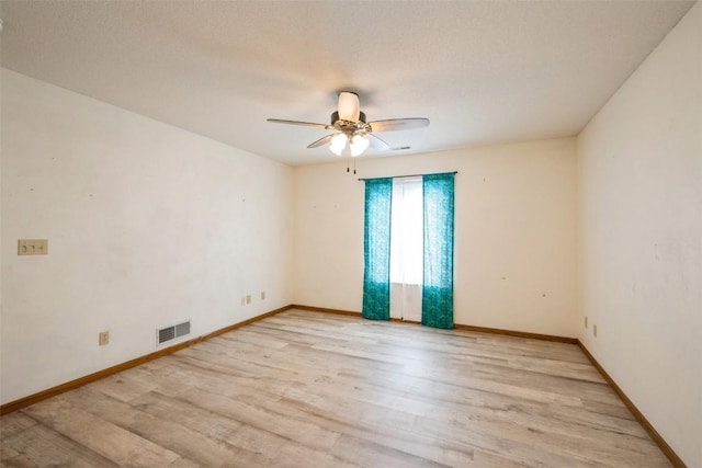 empty room featuring baseboards, ceiling fan, visible vents, and light wood-style flooring