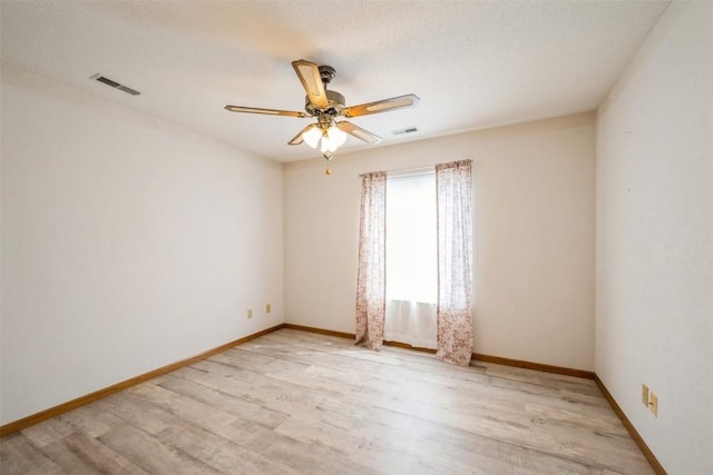 empty room featuring light wood-style floors, baseboards, a ceiling fan, and visible vents