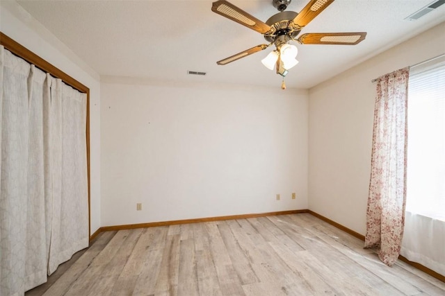 spare room with visible vents, a ceiling fan, light wood finished floors, and baseboards