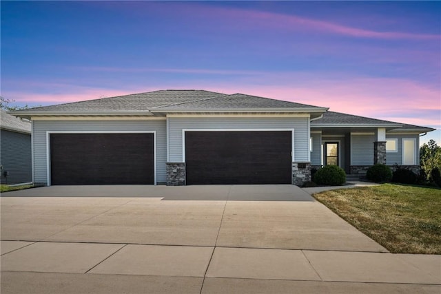 view of front of home featuring concrete driveway, an attached garage, stone siding, and a yard