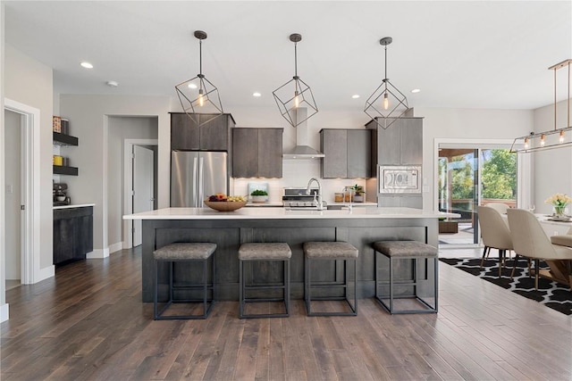 kitchen featuring light countertops, appliances with stainless steel finishes, dark wood-style flooring, and a kitchen bar