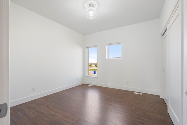 unfurnished bedroom featuring baseboards, a closet, and dark wood-style flooring