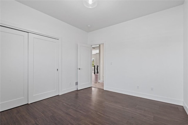 unfurnished bedroom with baseboards, dark wood finished floors, and a closet