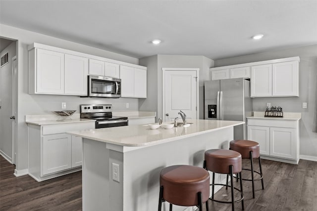 kitchen with dark wood-style flooring, baseboards, appliances with stainless steel finishes, and a sink