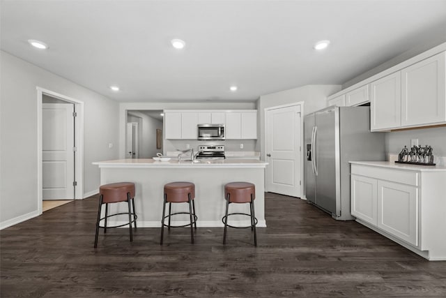 kitchen featuring a kitchen breakfast bar, appliances with stainless steel finishes, a center island with sink, recessed lighting, and white cabinetry