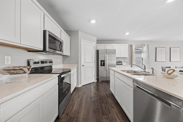 kitchen featuring white cabinets, dark wood-style flooring, appliances with stainless steel finishes, light stone counters, and a sink
