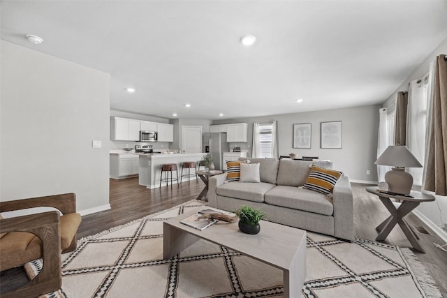 living area featuring baseboards, recessed lighting, and light wood-style flooring