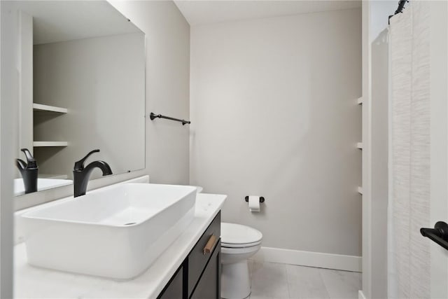 bathroom featuring baseboards, vanity, and toilet