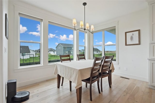 dining area with visible vents, baseboards, a chandelier, and light wood finished floors