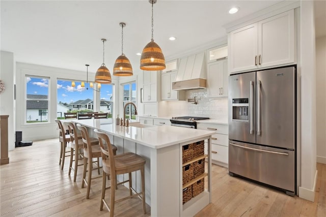 kitchen with a sink, light countertops, stainless steel appliances, recessed lighting, and custom exhaust hood