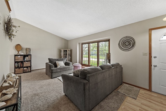 living room with baseboards, a textured ceiling, lofted ceiling, and light wood-type flooring