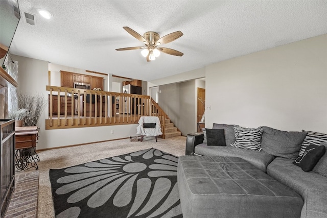 living room featuring a textured ceiling, carpet, a ceiling fan, visible vents, and stairway