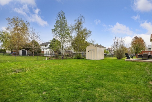 view of yard with a storage shed, an outbuilding, a fenced backyard, and a wooden deck