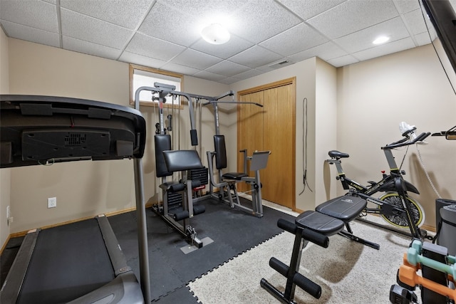 workout room featuring baseboards, visible vents, and a paneled ceiling
