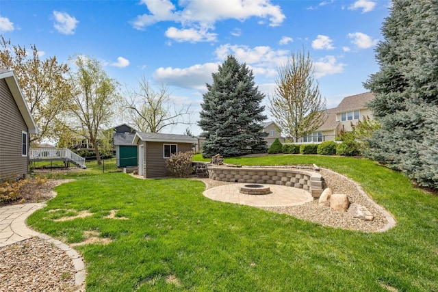 view of yard featuring a deck, a fire pit, and an outdoor structure