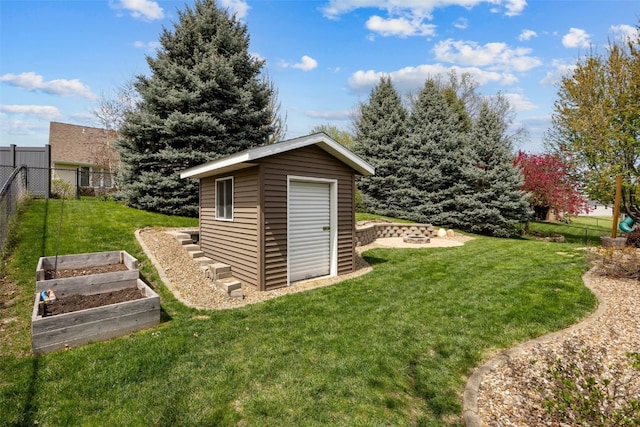 view of shed with fence, an outdoor fire pit, and a vegetable garden