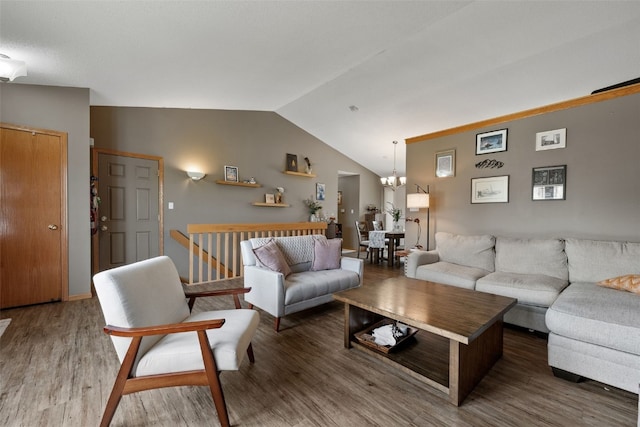 living area with vaulted ceiling, wood finished floors, and a notable chandelier