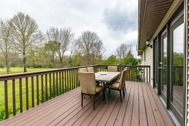 wooden deck featuring outdoor dining area and a lawn