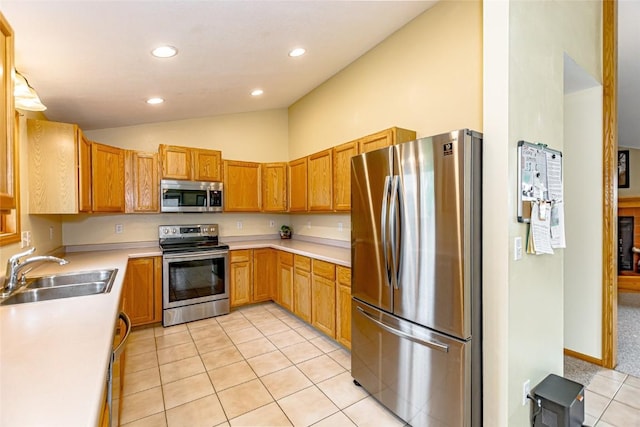 kitchen featuring recessed lighting, light countertops, a sink, appliances with stainless steel finishes, and vaulted ceiling