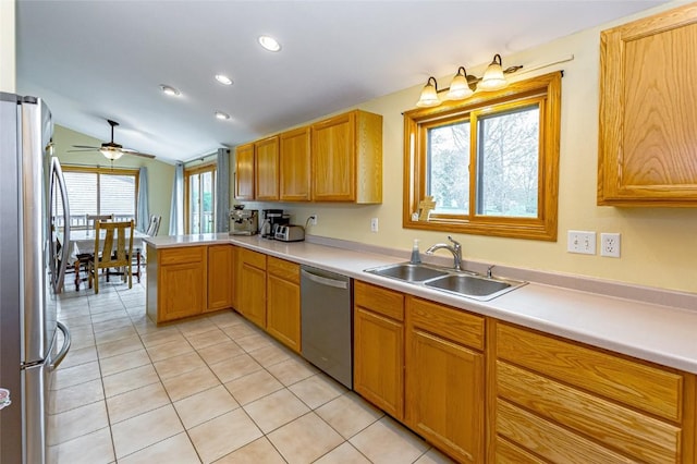 kitchen featuring light tile patterned flooring, a sink, stainless steel appliances, a peninsula, and vaulted ceiling