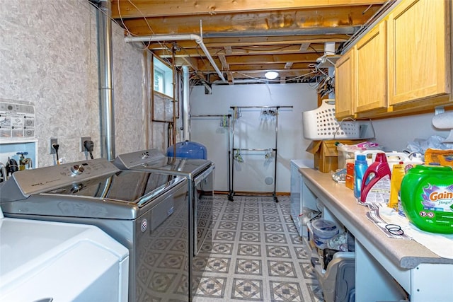 clothes washing area with separate washer and dryer and cabinet space