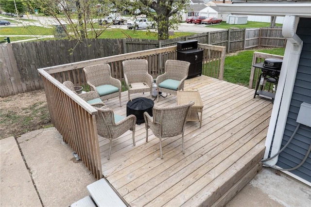 wooden deck featuring a fenced backyard, grilling area, an outdoor fire pit, and a residential view