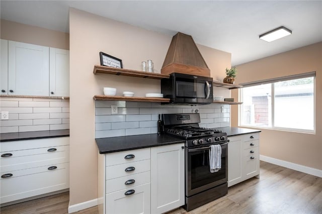 kitchen featuring black microwave, dark countertops, open shelves, stainless steel gas stove, and light wood finished floors