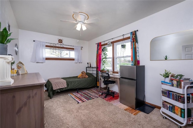 bedroom with freestanding refrigerator, ceiling fan, baseboards, and carpet