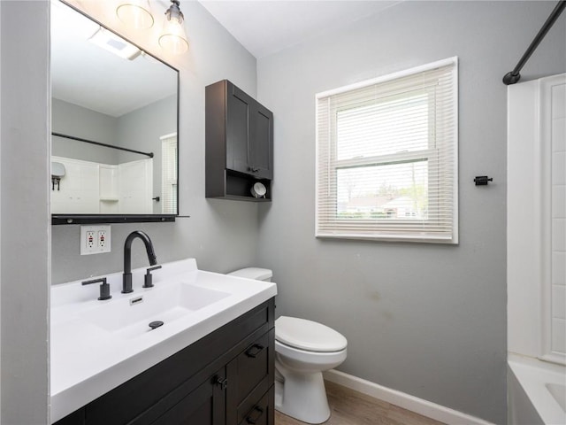bathroom with vanity, wood finished floors, toilet, baseboards, and shower / washtub combination