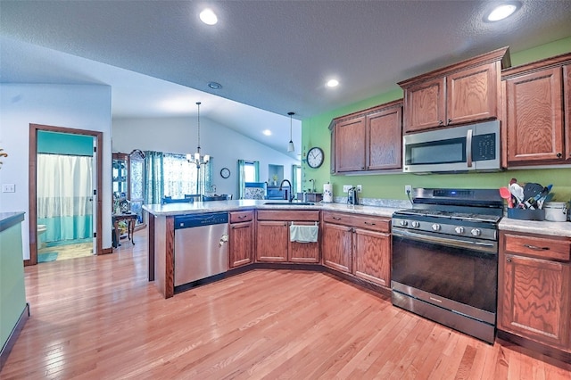 kitchen featuring a peninsula, a chandelier, a sink, vaulted ceiling, and stainless steel appliances