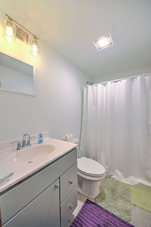 bathroom with vanity, toilet, curtained shower, and visible vents
