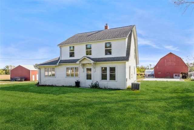view of front facade with an outdoor structure, a front yard, a chimney, a shingled roof, and a barn