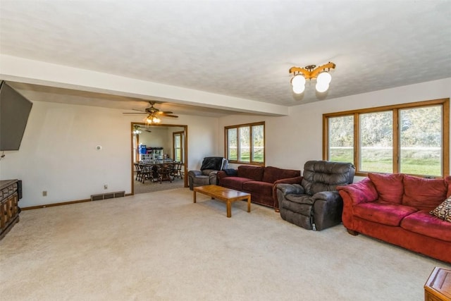 living area featuring baseboards, visible vents, ceiling fan, and light colored carpet