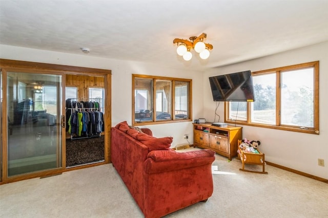 carpeted living area featuring baseboards and a notable chandelier