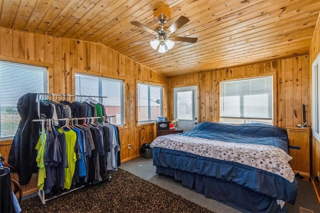 bedroom with wooden walls, multiple windows, and lofted ceiling