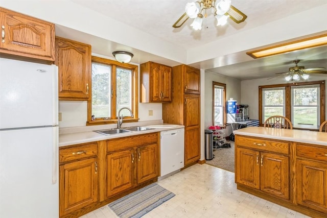kitchen featuring brown cabinetry, a sink, ceiling fan, and white appliances
