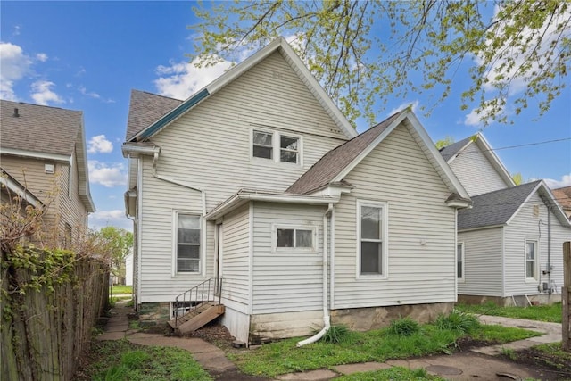 back of property featuring fence, entry steps, and roof with shingles