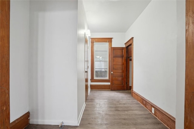 corridor featuring baseboards and wood finished floors