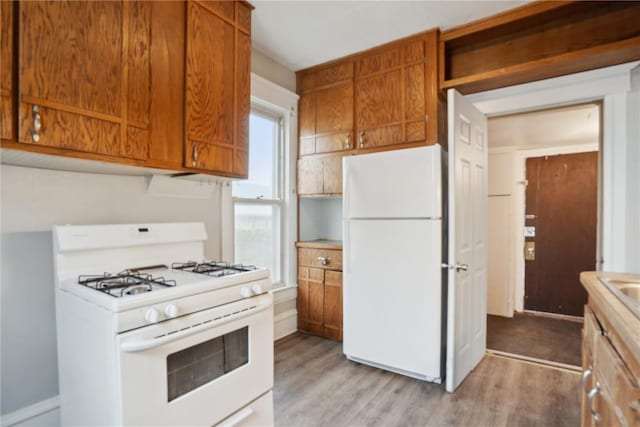 kitchen featuring light wood-style floors, light countertops, brown cabinets, and white appliances