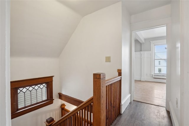 interior space featuring an upstairs landing, wood finished floors, vaulted ceiling, and a baseboard radiator