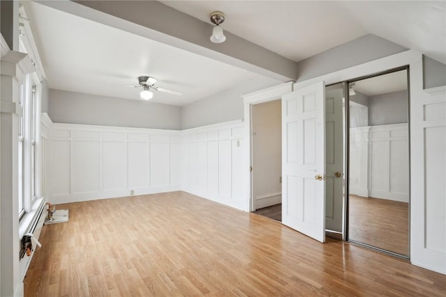 interior space with wood finished floors, a ceiling fan, a decorative wall, and a wainscoted wall