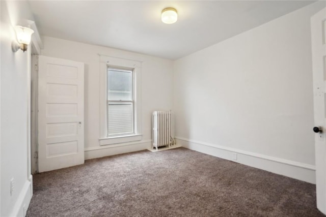 spare room with radiator, baseboards, and carpet