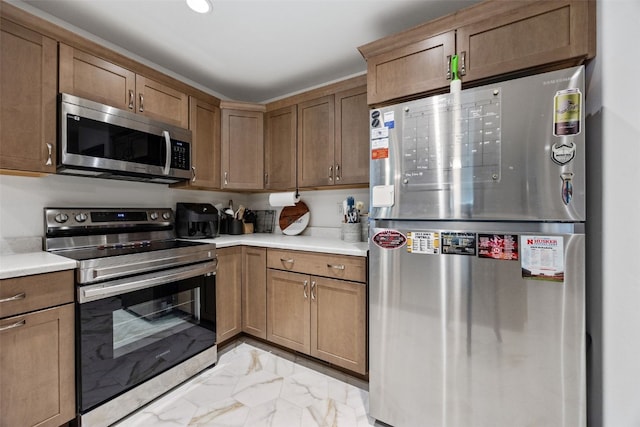 kitchen with light countertops, appliances with stainless steel finishes, brown cabinetry, and marble finish floor