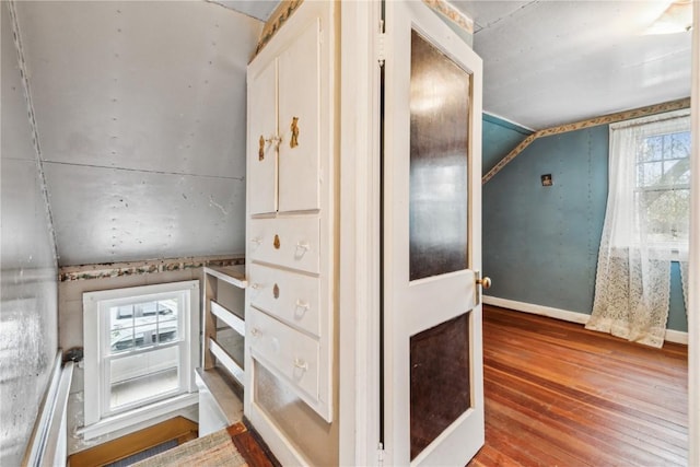 interior space with baseboards, lofted ceiling, and hardwood / wood-style floors