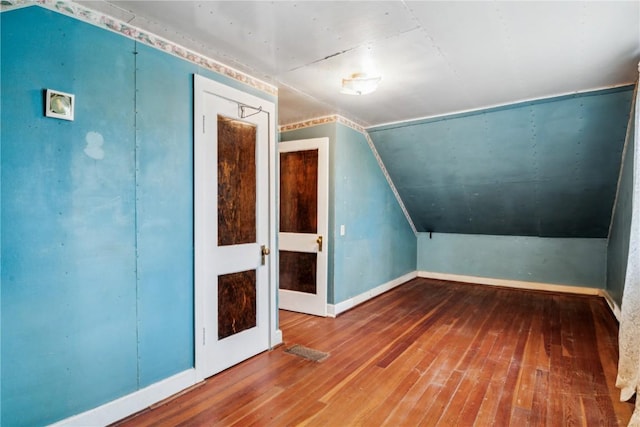additional living space featuring visible vents, baseboards, vaulted ceiling, and hardwood / wood-style flooring