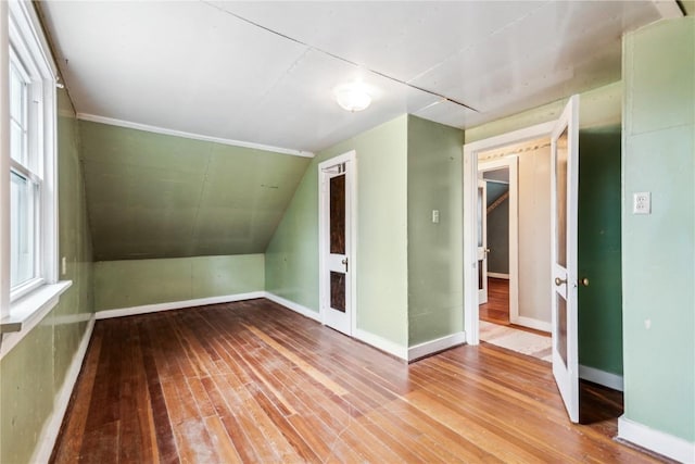 bonus room with wood-type flooring, baseboards, and vaulted ceiling