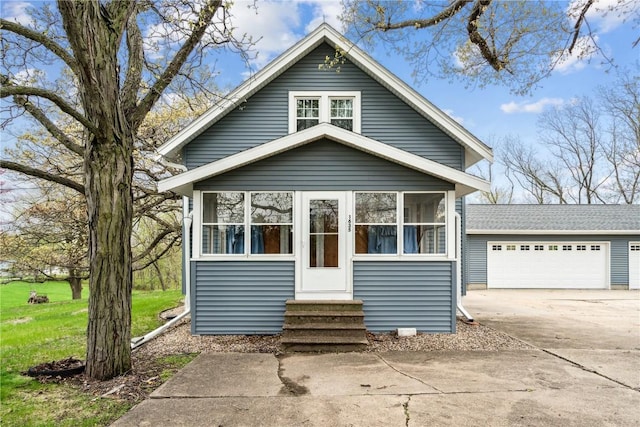 view of front of property with a sunroom, entry steps, and a detached garage