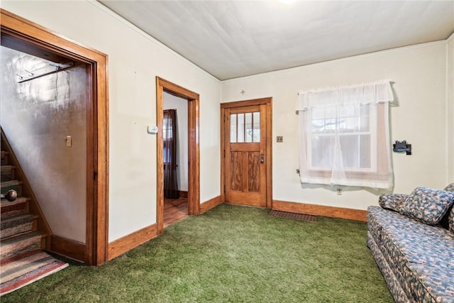 carpeted entryway featuring crown molding, baseboards, and stairs