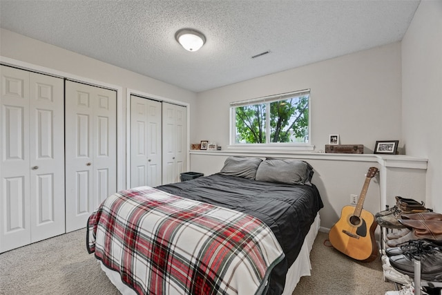 carpeted bedroom with multiple closets and a textured ceiling